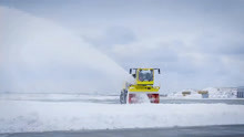 清理马路上的积雪的扫雪车，扬起的雪花漂亮极了